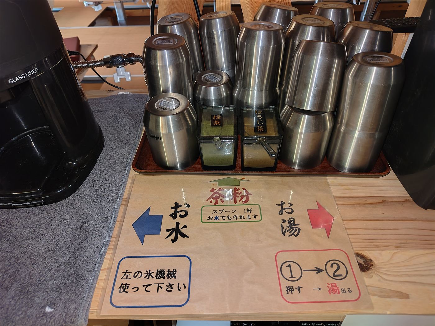 フリーコーナーの緑茶・ほうじ茶、コップと水・お湯のご案内